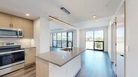 Located in Denver's vibrant LoHi neighborhood, this contemporary 3-bedroom, 2-bathroom home on Jason Street offers a thoughtfully designed single-floor layout with modern finishes throughout. The open-concept kitchen and living area serves as the heart of the home, anchored by a sleek waterfall-edge island with an integrated sink, warm wood cabinetry, subway tile backsplash, stainless steel appliances, and a striking linear pendant light. The living room extends naturally from the kitchen, featuring wide-plank hardwood floors, recessed lighting, a tray ceiling detail, and expansive floor-to-ceiling sliding glass doors that open to a private balcony with outdoor views. Each of the three bedrooms is finished with plush carpet and oversized black-framed windows that flood the rooms with natural light. The two bathrooms feature light wood vanities with quartz countertops and matte black hardware; one includes a full tub-shower combo with white subway tile surround. A dedicated in-unit laundry closet with a stacked washer and dryer adds everyday convenience. Three closets provide generous storage throughout. The clean, white palette and contemporary design elements create a bright, airy ambiance from room to room.
