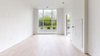 Located at 202 Burnhamthorpe Rd E in Mississauga, this thoughtfully designed two-bedroom, two-bathroom unit offers a clean, modern aesthetic across a single floor. Light-toned hardwood flooring flows seamlessly throughout the space, complementing the bright white walls and crisp baseboards that define the interior's contemporary character.

The entryway features a mirrored sliding closet and leads down a well-proportioned hallway into the heart of the unit. The open-concept kitchen and living area is a standout, anchored by a central island with a sleek quartz-style countertop. The kitchen is outfitted with light wood cabinetry, a white subway tile backsplash, and a full suite of stainless steel appliances including a refrigerator, stove, dishwasher, and over-the-range microwave. The living area benefits from expansive floor-to-ceiling windows that draw in abundant natural light and provide views of a landscaped outdoor terrace.

Both bedrooms are bright and well-proportioned, with the primary bedroom offering generous space and large windows overlooking greenery. The two bathrooms are finished with large-format stone-toned tiles — one featuring a soaker tub and vanity, the other a frameless walk-in shower with a built-in bench and mosaic tile flooring. A dedicated closet adds practical storage to round out this polished, move-in-ready residence.
