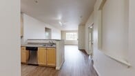 This well-designed apartment in Mill Creek, WA offers 980 square feet of thoughtfully arranged living space. The floor plan features two bedrooms, including a primary bedroom of 170 square feet, and two full bathrooms. The heart of the home is an open-concept living area, combining the kitchen and living room for a spacious feel. The kitchen is equipped with modern stainless steel appliances, light wood cabinetry, and ample counter space. A fireplace in the living room adds warmth and character. The apartment boasts a mix of flooring, with plush carpeting in bedrooms and sleek wood-look flooring in main living areas. Large windows provide natural light, while vertical blinds offer privacy control. The unit includes a dedicated laundry room with full-size washer and dryer. Generous closet space in bedrooms and throughout the apartment ensures plenty of storage. The bathrooms feature clean lines with wood vanities and shower/tub combinations. Overall, this apartment offers a comfortable and functional living space with contemporary finishes.
