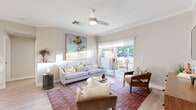 This thoughtfully designed single-floor residence offers a seamless blend of modern finishes and inviting warmth throughout its well-proportioned layout. The open-concept living area serves as the heart of the home, featuring light wood-look flooring, crown molding, and a ceiling fan overhead. Large sliding glass doors flood the space with natural light and open directly onto a private patio, providing a relaxed outdoor extension of the living area. The living room comfortably accommodates multiple seating arrangements and includes a wall-mounted television with a warm wood media console.

The kitchen is both functional and visually appealing, outfitted with crisp white shaker-style cabinetry, sleek quartz countertops, a neutral subway tile backsplash, and stainless steel appliances including a range with a wall-mounted hood, a dishwasher, and a refrigerator. A dedicated pantry and a breakfast bar with bar seating add to the kitchen's practicality.

The bedroom is a comfortable retreat, featuring plush carpeting, large windows with blinds for natural light and privacy, and ample space for furnishings. The bathroom is clean and modern, with a white vanity, quartz countertop, wood-look tile flooring, and a well-lit mirror. Throughout the residence, neutral tones and quality finishes create a cohesive and polished aesthetic.