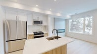 This contemporary townhouse in Calgary offers 66 square meters of living space spread across two floors. The property boasts three bedrooms, including a primary bedroom of 10 square meters, and two bathrooms. The ground floor spans 34 square meters, while the upper floor covers 32 square meters.

The kitchen is a highlight, featuring modern appliances, including a stainless steel refrigerator and range. It showcases a sleek design with white cabinetry, light wood accents, and a spacious island, perfect for meal preparation and casual dining. The open-concept layout seamlessly connects the kitchen to the living areas, enhanced by recessed lighting and large windows that flood the space with natural light.

The bathrooms are stylishly appointed, with one featuring a glass-enclosed shower with modern fixtures. Light-toned tiles, wooden vanities, and black hardware create a contemporary aesthetic. Throughout the home, light wood flooring adds warmth and continuity to the crisp white walls.

Bedrooms are bright and airy, with ample natural light from well-placed windows. Built-in closets provide practical storage solutions. The property also includes two staircases and a hallway, ensuring easy navigation between floors and rooms.

Overall, this townhouse combines modern design with functional living spaces, offering a fresh and inviting atmosphere in a prime Calgary location.