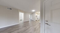 This single-floor, 3-bedroom, 1-bathroom residence in Breakers, US, offers a clean and modern aesthetic throughout. The open-concept living and dining area is a standout feature, showcasing light gray wood-look flooring, neutral-toned walls, and a sliding glass door that fills the space with natural light and provides views of the surrounding greenery. The galley-style kitchen is efficiently designed with white cabinetry, granite-look countertops, white appliances including a range, dishwasher, and refrigerator, complemented by matching wood-look flooring. A hallway connects the living area to the private sleeping quarters, where the spacious primary bedroom offers generous square footage, plush carpeting, and access to a well-sized walk-in closet with built-in shelving rods. The two additional bedrooms also feature soft carpeting and ample natural light. The full bathroom is bright and clean, appointed with a tub-shower combo, white vanity with stone-look countertop, and light wood flooring. A dedicated laundry area with washer/dryer hookups adds everyday convenience. Three closets throughout the home ensure excellent storage capacity, making this a highly functional and comfortable living space.