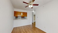 Located at 600 Texas St in Denton, TX, this single-floor unit offers a practical and well-organized layout that makes efficient use of its space. The open living area is finished with warm-toned laminate flooring that runs throughout, creating a cohesive look and easy maintenance. A ceiling fan with a built-in light fixture anchors the main living area, providing both air circulation and ambient lighting. Natural light enters through a window near the front entry door, brightening the space.

The kitchen is defined by a pass-through design with a countertop bar that opens to the living area, promoting an open and connected feel. Warm wood-toned upper cabinetry with matching lower cabinets provides functional storage, while a refrigerator and countertop workspace complete the kitchen setup. The pass-through overhang doubles as a casual dining or prep surface.

The bathroom is clean and functional, featuring a wood-toned vanity with a white countertop and integrated sink, a wall-mounted mirror with overhead lighting, and a full tub-shower combination. The same laminate flooring continues into the bathroom, maintaining design consistency.

A dedicated closet provides organized storage, and the white walls throughout give the space a bright, neutral backdrop that lends itself to personalization. Overall, this unit offers a functional and straightforward layout in a convenient Denton location.