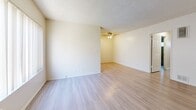 Located at 217 W. Tujunga Ave. in Burbank, CA, this single-floor unit offers 2 bedrooms and 2 bathrooms within a efficiently designed layout. The open-concept living, dining, and kitchen area serves as the heart of the home, featuring light wood-style flooring, a textured ceiling, and a large window with vertical blinds that invites natural light into the space. A wall-unit air conditioner and ceiling fan provide climate comfort throughout. The kitchen is equipped with gray cabinetry, a gas cooktop, double wall ovens, a range hood, and a tiled backsplash, offering functional preparation space. Both bedrooms are carpeted for comfort, with the primary bedroom featuring a high horizontal window and generous square footage. The secondary bedroom includes a sliding mirrored closet door. In total, four closets provide abundant storage throughout the unit. The two bathrooms are finished with light wood-style flooring and gray vanity cabinetry. One bathroom features a tub/shower combination with white tile surround, while the other offers a vanity with a large mirror. A connecting hallway ties all rooms together in a practical and accessible flow. The unit's neutral color palette and clean finishes create a bright, move-in-ready atmosphere.