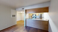 This two-bedroom, one-bathroom residence in Tucson, Arizona offers a practical and well-organized single-floor layout. The open-concept living and kitchen area serves as the heart of the home, where rich hardwood-style flooring extends throughout. The kitchen features light wood cabinetry, stainless steel appliances including a refrigerator, range, microwave, and dishwasher, complemented by a breakfast bar peninsula that doubles as a functional divider between the kitchen and living space. The living area is bright and open, with a sliding glass door that allows natural light to pour in and provides access to the outdoors.

Both bedrooms are carpeted for comfort and are naturally lit by windows with vertical blinds offering outdoor views. The spacious primary bedroom includes a walk-in closet with built-in shelving, providing generous storage. The second bedroom features a sliding closet with a hanging rod. The full bathroom is clean and functional, complete with a tiled shower-tub combination and hardwood-style flooring. Throughout the residence, neutral tones and clean finishes create a cohesive, move-in-ready atmosphere suited for comfortable everyday living in the Tucson area.