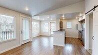 Located at 61560 Aaron Way in Bend, Oregon, this 2-bedroom, 2-bathroom single-floor home offers a well-designed layout that balances comfort and functionality. The open-concept living and kitchen area is anchored by warm hardwood-style flooring that flows throughout the main spaces, while recessed lighting and multiple windows allow generous natural light to fill the interior. A sliding barn door adds a stylish architectural accent near the entryway.

The kitchen is thoughtfully appointed with granite-style countertops, taupe cabinetry, a stainless steel refrigerator, gas range, and built-in microwave. A central island with a sink provides additional prep space and connects the kitchen to the living area. The living room features a tile-surround fireplace and a window overlooking the outdoor surroundings.

Both bedrooms are carpeted for comfort, with the primary bedroom offering a closet and sliding glass door access to a private balcony. The second bedroom is bright with dual windows and hardwood-style flooring. Each bathroom is finished with tile flooring, granite-topped vanities, and taupe cabinetry consistent with the home's cohesive design. A hallway with additional closet space completes this efficient and well-appointed Bend residence.