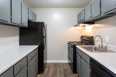 Located at 1355 Graves Rd in Norcross, Georgia, this single-floor unit offers a practical and well-maintained layout with a clean, neutral aesthetic throughout. The main living area is expansive and open, showcasing rich wood-look flooring, crisp white walls, and a textured ceiling. Natural light streams in through a large sliding glass door fitted with vertical blinds, creating a bright and welcoming atmosphere. Crown molding adds a refined touch to the living and dining areas, which flow seamlessly into one another, with a pendant light fixture marking the transition.

The kitchen is equipped with dark cabinetry, light speckled countertops, and a black electric range with an overhead ventilation hood, providing a functional cooking space. The open-concept dollhouse view reveals a well-organized layout connecting the living, dining, and kitchen areas efficiently.

The bedroom features plush carpet flooring and benefits from multiple windows that allow ample natural light to fill the room, offering views of surrounding greenery. The bathroom is finished with dark gray cabinetry, a wide white countertop, a large wall mirror with Hollywood-style lighting, and wood-look flooring that ties back to the rest of the unit. A separate shower stall completes the space. Throughout, the unit maintains a consistent, neutral palette that lends itself to easy personalization.
