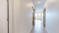 Located at 4757 Hiawatha Ave in Minneapolis, this thoughtfully designed one-bedroom, one-bathroom unit offers a clean, contemporary aesthetic throughout. Light wood-style flooring flows through the main living areas, complemented by crisp white walls and recessed lighting that keep the space feeling bright and open.

The open-concept kitchen, dining, and living area serves as the heart of the unit. The kitchen is outfitted with white shaker cabinetry, a white subway tile backsplash, stainless steel appliances including a built-in microwave and electric range, and a sleek countertop workspace. Track lighting overhead adds both function and style. A floor-to-ceiling glass door leads to a private balcony, flooding the living and dining area with abundant natural light and offering pleasant outdoor views.

A hallway with a distinctive sliding barn door connects the main living area to the private quarters. The bedroom features plush carpeting, a large closet with built-in shelving, and a window that brings in natural light. The bathroom includes a full soaking tub with white tile surround and wood-look flooring. A dedicated laundry area rounds out the functional layout of this well-appointed unit, making it a complete and comfortable living space.