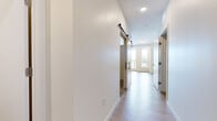 Located at 4757 Hiawatha Ave in Minneapolis, this thoughtfully designed one-bedroom, one-bathroom unit offers a clean, contemporary aesthetic throughout. Light wood-style flooring flows through the main living areas, complemented by crisp white walls and recessed lighting that keep the space feeling bright and open.

The open-concept kitchen, dining, and living area serves as the heart of the unit. The kitchen is outfitted with white shaker cabinetry, a white subway tile backsplash, stainless steel appliances including a built-in microwave and electric range, and a sleek countertop workspace. Track lighting overhead adds both function and style. A floor-to-ceiling glass door leads to a private balcony, flooding the living and dining area with abundant natural light and offering pleasant outdoor views.

A hallway with a distinctive sliding barn door connects the main living area to the private quarters. The bedroom features plush carpeting, a large closet with built-in shelving, and a window that brings in natural light. The bathroom includes a full soaking tub with white tile surround and wood-look flooring. A dedicated laundry area rounds out the functional layout of this well-appointed unit, making it a complete and comfortable living space.