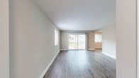 Located at 122 Pinewood Crescent in Yorktown, Virginia, this single-story 2-bedroom, 2-bathroom home offers a clean, modern aesthetic with thoughtfully updated finishes throughout. The open living and dining areas are anchored by durable wood-look plank flooring in a warm gray tone, neutral wall colors, and crisp white trim that together create a bright, cohesive atmosphere. Sliding glass doors in the living room invite natural light and provide direct access to an outdoor deck, further enhancing the sense of openness. The galley-style kitchen is well-equipped with white shaker cabinetry, brushed nickel hardware, light quartz countertops, a double stainless steel sink, and stainless steel appliances — all set over matching wood-look flooring. An adjacent dining area with a window adds practicality and natural light to the space. Both bedrooms are generously sized, featuring plush carpet, neutral tones, and ample natural light from well-placed windows. The spacious primary bedroom includes multiple closets for abundant storage. The bathrooms continue the home's clean design with wood-look flooring and light finishes. A dedicated utility room and five closets throughout the home provide exceptional storage. The layout flows efficiently through a connecting hallway, making the home functional and easy to navigate.