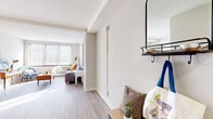 Located at 330 Oak Grove St in Minneapolis, MN, this efficiently designed studio offers a well-organized single-floor layout comprising a living room, bathroom, and hallway. The living area is the heart of the unit, bathed in natural light streaming through large windows fitted with horizontal blinds. Light hardwood-style flooring runs throughout the space, complementing the neutral, warm-toned walls and creating a cohesive, airy aesthetic. A kitchenette is neatly tucked into an alcove, featuring white cabinetry, a compact sink, and counter space — an efficient and functional setup. The entryway hallway provides a practical transition into the living area, complete with wall-mounted hooks, a shelf, and a mirror, offering useful storage and organization options right at the entrance. The bathroom includes a full soaking tub with white tile surround and a shower curtain, finished with clean, bright fixtures. Throughout the unit, recessed and flush-mount ceiling lighting supplements the natural light, ensuring the space remains well-lit at all times. The overall ambiance is clean, modern, and welcoming, with a layout that maximizes every square foot efficiently.