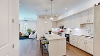 Located at 4343 Woodhead St in Houston's sought-after Montrose/Upper Kirby area, this thoughtfully designed 2-bedroom, 2-bathroom residence offers a refined single-level layout with high-end finishes throughout. The open-concept living room is bright and welcoming, featuring hardwood flooring, recessed lighting, a ceiling fan, and direct access to a private balcony with iron railings and views of the brick exterior courtyard. The gourmet kitchen is a standout, outfitted with custom shaker cabinetry, quartz countertops, a marble-tile backsplash, stainless steel appliances including a professional-grade range, a built-in wine cooler, a central island with seating, and elegant pendant lighting. The spacious primary bedroom features large floor-to-ceiling windows, balcony access, hardwood floors, and a tray ceiling with ceiling fan. Its en-suite bathroom is luxuriously appointed with full marble-look tile, a soaking tub, an illuminated vanity mirror, and a dual-sink white cabinetry vanity. The second bathroom mirrors the same refined aesthetic. Three well-organized closets, including a carpeted walk-in with adjustable shelving systems, provide ample storage throughout the residence.