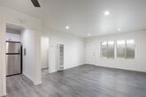 Located on Delaware Street in Huntington Beach, California, this single-story home showcases a clean, modern aesthetic carried consistently throughout every room. Light-toned luxury vinyl plank flooring runs throughout the entire space, lending a cohesive and contemporary feel underfoot while reflecting natural light from the numerous windows fitted with horizontal blinds.

The living area is bright and open, with recessed lighting and a ceiling fan complementing natural light that filters in through a large front-facing window. The layout flows naturally into the additional rooms, each of which features a ceiling fan with integrated lighting, neutral cream walls, and ample window space that brings in views of the surrounding greenery.

The kitchen stands out as a well-appointed space featuring white shaker-style cabinetry extending to the ceiling, quartz-look countertops, a stainless steel gas range, and an over-the-range microwave. Multiple windows allow natural light to brighten the workspace, and a secondary door provides convenient exterior access.

The bathroom is finished with clean white subway tile surrounding the tub-shower combination, accented by brushed gold fixtures that add a warm, refined touch. A frosted window above the tub provides privacy while maintaining natural light. Overall, the home presents a fresh, move-in-ready interior with consistent modern upgrades throughout.
