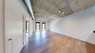 Located at 1025 N Fillmore St in Arlington, Virginia, this single-floor residence offers a compelling blend of industrial design and modern finishes. The open-concept living area immediately impresses with its exposed concrete ceiling, visible ductwork, and track lighting, creating a distinctly urban loft aesthetic. Large black-framed windows flood the space with natural light and provide views of the surrounding cityscape.

The kitchen is well-appointed with light wood cabinetry, dark granite countertops, a subway tile backsplash, and a full suite of stainless steel appliances including a refrigerator, range, and microwave. A peninsula with a generous granite countertop connects the kitchen seamlessly to the living area, making it ideal for both cooking and entertaining.

The bedroom features its own black-framed window with outdoor access, a ceiling fan mounted to the exposed concrete ceiling, and ample space for furnishings. Additional rooms offer the same consistent hardwood-style flooring and clean white walls throughout.

The bathroom stands out with elegant marble-style tile covering the walls and surrounding a soaking tub and a separate glass-enclosed shower. A wood vanity with a dark granite countertop and a large mirror completes this refined space. Overall, the residence delivers an industrial-modern ambiance with high-quality finishes throughout.