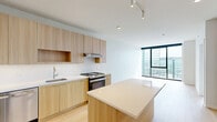 Located in Chicago's vibrant Lincoln Park/Clybourn Corridor neighborhood, this high-rise unit at 1475 N Kingsbury St offers a thoughtfully designed one-bedroom, two-bathroom layout with a clean, contemporary aesthetic throughout. Light-toned hardwood flooring runs continuously across the entire space, complementing the crisp white walls and creating a bright, cohesive feel.

The open-concept kitchen and living area serves as the heart of the unit. The kitchen is outfitted with flat-front light wood cabinetry, white quartz countertops, a textured tile backsplash, and a full suite of stainless steel appliances including a gas range, dishwasher, and French door refrigerator. A central island provides additional prep space and casual seating.

Floor-to-ceiling windows in the living area and bedroom flood the space with natural light and frame sweeping views of the Chicago skyline. A structural column in the bedroom adds an architectural accent without compromising the room's open feel. The bedroom includes access to a well-organized walk-in closet with built-in shelving and hanging systems. The bathrooms feature clean tile flooring and a tub-shower combination. A dedicated walk-in closet off the main living area provides generous additional storage.