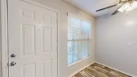 This single-floor residence offers a practical and comfortable layout with a clean, neutral aesthetic throughout. The entry area welcomes you with wood-look tile flooring and a large window fitted with horizontal blinds that allows natural light to filter in softly. A ceiling fan overhead adds to the airy feel of the space.

The galley-style kitchen is efficiently designed, featuring white cabinetry, light granite-look countertops, a stainless steel double-basin sink, a dishwasher, an electric range, and a stainless steel refrigerator. The wood-look flooring continues through this space, tying the common areas together cohesively.

The bedrooms are carpeted for warmth and comfort, each equipped with ceiling fans and windows with blinds that provide ample natural light. The rooms offer a calm, neutral palette with light gray walls and white trim throughout.

The bathroom is well-appointed with a full tub-shower combination, a white vanity with granite-look countertops, and matching wood-look tile flooring that complements the rest of the home. Towel bars and a mirror complete the functional layout.

The textured ceilings and consistent trim work give the space a cohesive and tidy appearance. Overall, the residence presents a clean, move-in-ready environment with practical finishes and a comfortable, functional flow from room to room.