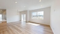 This single-floor home offers a thoughtfully designed layout encompassing four bedrooms, two bathrooms, a kitchen, dedicated laundry room, hallway, and closet. Light-toned hardwood flooring flows consistently throughout every room, creating a cohesive and contemporary aesthetic.

The open living area is bright and airy, featuring recessed lighting, a decorative chandelier, sliding glass door access to the exterior, and a large picture window framing views of the surrounding neighborhood and distant mountains. Natural light fills the space generously throughout the day.

The kitchen is outfitted with flat-front light wood cabinetry extending to the ceiling for ample storage, white quartz countertops, a stainless steel gas range, over-the-range microwave, and a side-by-side refrigerator. A central island with an integrated sink adds functional workspace.

The bedrooms feature clean white walls, hardwood floors, and panel-style doors. One bedroom benefits from a neighborhood-facing window with mountain views. The dedicated laundry room includes upper wood cabinetry and appliance hookups.

Both bathrooms maintain the home's modern palette with light wood vanities, white quartz countertops, and matte black hardware. The primary bathroom includes a glass-enclosed tile shower, while the secondary bathroom features a tiled tub surround.