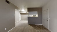 This single-floor residence offers a practical and well-organized layout designed for comfortable everyday living. The open living and dining area is finished with plush wall-to-wall carpeting and neutral taupe-toned walls, creating a warm and cohesive atmosphere throughout. A distinctive two-toned accent wall separates the living space from the kitchen, where a pass-through counter with a raised bar provides both visual connection and casual dining convenience. The galley-style kitchen is efficiently designed with white cabinetry extending to the ceiling for ample storage, light wood-look flooring, granite-style countertops, and a full suite of stainless steel appliances including a refrigerator, stove, microwave, and dishwasher. A door at the end of the kitchen provides additional access. The bedroom is generously proportioned with soft carpet, a ceiling fan, and a window fitted with blinds that allows natural light to fill the room. An adjacent closet offers dedicated storage space. The bathroom features a tub-shower combination, a granite-topped vanity with an undermount sink, and light wood-look tile flooring. A large sliding-door closet adjacent to the bathroom adds further storage capacity to the space.