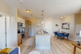This thoughtfully designed 2-bedroom, 2-bathroom residence in Medford, MA offers a functional and modern open-concept floor plan across a single level. The heart of the home is a sleek kitchen featuring stainless steel appliances, a subway tile backsplash, warm wood cabinetry, and a central island with an integrated sink and pendant lighting overhead — ideal for both cooking and casual dining. The kitchen flows seamlessly into the combined dining and living area, which is bathed in natural light and opens directly onto a private balcony through sliding glass doors, offering outdoor space and pleasant views. The living room is generously proportioned with light hardwood-style flooring that extends throughout the main living areas. The spacious primary bedroom is carpeted for comfort and includes dedicated closet space with built-in shelving. The second bedroom is equally well-sized. Both bathrooms are finished with white subway tile surrounds in the tub/shower, wood-toned vanity cabinetry, and large mirrors. Three closets provide ample storage throughout the unit. Additional conveniences include a dedicated laundry area and a utility room. The overall aesthetic is clean and contemporary, with neutral tones and modern finishes throughout.