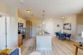This thoughtfully designed 2-bedroom, 2-bathroom residence in Medford, MA offers a functional and modern open-concept floor plan across a single level. The heart of the home is a sleek kitchen featuring stainless steel appliances, a subway tile backsplash, warm wood cabinetry, and a central island with an integrated sink and pendant lighting overhead — ideal for both cooking and casual dining. The kitchen flows seamlessly into the combined dining and living area, which is bathed in natural light and opens directly onto a private balcony through sliding glass doors, offering outdoor space and pleasant views. The living room is generously proportioned with light hardwood-style flooring that extends throughout the main living areas. The spacious primary bedroom is carpeted for comfort and includes dedicated closet space with built-in shelving. The second bedroom is equally well-sized. Both bathrooms are finished with white subway tile surrounds in the tub/shower, wood-toned vanity cabinetry, and large mirrors. Three closets provide ample storage throughout the unit. Additional conveniences include a dedicated laundry area and a utility room. The overall aesthetic is clean and contemporary, with neutral tones and modern finishes throughout.