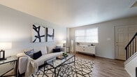 This thoughtfully designed multi-floor residence spans three levels and offers a clean, contemporary aesthetic throughout. The main living area is bright and welcoming, featuring warm hardwood-style flooring, soft neutral walls, and a generous window that fills the room with natural light. The space comfortably accommodates both a seating area and a separate dining nook, the latter complete with its own window and wall art that adds a touch of refinement.

The kitchen is efficiently laid out with white cabinetry, light granite-style countertops, stainless steel appliances including an electric range, and a dishwasher — combining both style and functionality. Adjacent living spaces maintain the same warm, cohesive palette, offering versatile areas ideal for relaxing or entertaining.

The bedroom features soft, neutral tones, wood-look flooring, and a full-width closet with bi-fold doors accented by brushed gold hardware, providing generous storage. The bathroom is clean and well-maintained, with a tiled tub-shower combination and wood-look vinyl flooring.

The lower level offers a spacious, carpeted room with a small window — a flexible space well-suited for use as a home office, recreation room, or additional storage. Throughout all three floors, the consistent use of neutral tones, modern finishes, and natural light creates a cohesive and comfortable living environment.