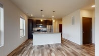 Located at 1430 Whiterock Ave in Waukesha, Wisconsin, this single-floor residence offers a thoughtfully designed layout with contemporary finishes throughout. The heart of the unit is an open-concept kitchen and living area, where light wood-tone luxury vinyl plank flooring ties the space together seamlessly. The kitchen is outfitted with dark espresso cabinetry, stainless steel appliances including a refrigerator, range, and over-the-range microwave, and a large central island topped with granite countertops. Pendant lighting hangs above the island, complementing the recessed ceiling lights, while a window along the adjacent wall invites natural light into the space.

The bedrooms feature plush carpeting and generously sized windows that frame views of the surrounding greenery, creating a bright and comfortable atmosphere. Two bathrooms serve the unit — one featuring a walk-in shower with a dark-toned vanity and tile flooring, and the other offering a full tub/shower combination with a navy cabinetry vanity, large mirror, and matching tile flooring. Throughout the unit, clean neutral wall tones and modern hardware contribute to a cohesive, contemporary aesthetic that is both functional and visually appealing.