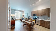 Located at 2803 Poag St in Alexandria, VA, this one-bedroom, two-bathroom residence offers a thoughtfully designed single-floor layout that maximizes every square foot. The open-concept kitchen and living area serves as the heart of the home, featuring wood-toned cabinetry extending to the ceiling, stainless steel appliances, a tile backsplash, white quartz countertops, and a kitchen island ideal for dining or entertaining. Light wood-style flooring flows throughout the main living areas, complementing the neutral color palette. The living room is bathed in natural light through oversized floor-to-ceiling windows that frame views of the surrounding streetscape and greenery, creating a bright and welcoming atmosphere. The bedroom continues the design aesthetic with a striking navy accent wall at chair-rail height, soaring ceilings, and a large window overlooking lush outdoor foliage. The bathroom is finished with clean white subway tile, a tub-shower combination, and a sleek dark wood vanity with ample counter space. A dedicated closet and convenient in-unit stacked washer and dryer add practical functionality. Throughout the residence, the combination of elevated finishes, generous natural light, and contemporary design elements creates a polished and comfortable living environment.
