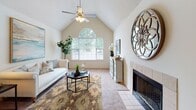 This thoughtfully designed 2-bedroom, 2-bathroom single-story residence offers a comfortable and functional layout. The living room is an immediate highlight, featuring dramatic vaulted ceilings with a textured finish, a ceiling fan with light fixture, and a large arched window that floods the space with natural light and offers views of surrounding greenery. A tile-surround fireplace anchors one wall, adding warmth and character to the room. Soft carpeting and neutral tones throughout create an inviting atmosphere.

The kitchen is efficiently laid out with light wood cabinetry, white appliances including a refrigerator, dishwasher, and range, and a stainless steel sink with ample counter space. A pass-through counter connects the kitchen to a casual dining area, enhancing the open feel of the space.

The primary bedroom offers comfortable proportions with plush carpeting and direct access to a closet. The second bedroom also features carpet, a dedicated closet, and a window with natural light. Both bathrooms are finished with tile flooring, single-sink vanities with wood cabinetry, and well-lit mirrors. The overall design is clean and neutral, providing a versatile backdrop suited to a variety of living styles.