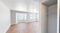 This single-floor, one-bedroom, one-bathroom residence offers a thoughtfully laid-out floor plan that makes efficient use of its space. The living area is a standout feature, highlighted by a distinctive bay window arrangement that floods the room with natural light and creates an open, airy atmosphere. Warm hardwood-style flooring flows throughout the main living areas, complemented by neutral gray walls and clean white trim. A ceiling fan adds both function and a classic touch to the living space.

The kitchen is efficiently designed with a galley-style layout, featuring white cabinetry, dark granite-look countertops, a stainless steel sink, and white appliances including a refrigerator and dishwasher. The hardwood-style flooring continues here, tying the kitchen seamlessly to the rest of the home.

The generously proportioned primary bedroom offers plush wall-to-wall carpeting, a window with blinds for natural light and privacy, and notably, two side-by-side double closets with bifold doors — providing ample storage. The bathroom is clean and functional, featuring a full tub and shower combo enclosed with classic white square tile surround and chrome fixtures. A connecting hallway ties all rooms together in a practical and accessible layout.