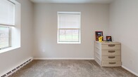 Located at 611 Manor Village in Bath, NY, this two-bedroom, one-bathroom unit offers a practical and well-organized single-floor layout. The combined living and dining area serves as the central gathering space, featuring neutral-toned carpet flooring, clean white walls, and flush ceiling lighting. A hallway connects the main living areas to the private quarters, maintaining a clear and functional flow throughout.

The kitchen is a standout feature, outfitted with modern light wood cabinetry, gray subway tile backsplash, light quartz-style countertops, and black stainless steel appliances including a refrigerator, gas range, and dishwasher. Light vinyl flooring and a window overlooking the outdoors add brightness to the space.

Both bedrooms are carpeted and feature windows that bring in natural light with views of the surrounding greenery. The primary bedroom is a comfortable size and includes baseboard heating. A second bedroom offers similar finishes and additional dresser storage. Two closets provide practical storage solutions throughout the unit.

The bathroom includes a tub/shower combination and standard white fixtures. A connecting hallway with additional closet access ties the layout together efficiently, making this a well-appointed and move-in ready home.