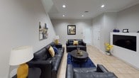 This two-floor home offers a thoughtfully designed layout with distinct living spaces spread across both levels. The main living area is anchored by recessed lighting, light tile flooring, and crown molding, and is furnished with a black leather seating arrangement complemented by bold navy and gold accent pieces. Abstract wall art and staircase details add visual interest to the open, airy atmosphere.

The kitchen is a functional centerpiece, featuring cream-toned raised-panel cabinetry, granite countertops, a center island with bar seating, and stainless steel appliances including a gas range, microwave, and refrigerator. Light tile flooring and a window with blinds complete the bright, well-equipped space.

Adjacent to the kitchen, the dining area accommodates a dark oval table surrounded by vibrant yellow chairs beneath a multi-bulb chandelier. A decorative circular wall piece serves as a focal point in the room.

The bedrooms are finished with neutral carpet and window blinds, offering a calm retreat. One bedroom includes a spacious walk-in closet with dual hanging rods along three walls. A full bathroom features tile flooring, a tub-shower combination with tile surround, and granite vanity countertop.