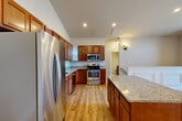 Located at 1100 Hunters Run Dr in Grand Blanc, Michigan, this two-story home offers a thoughtfully designed layout across two levels. The main living floor hosts the primary living spaces, including a spacious kitchen equipped with rich cherry wood cabinetry, granite countertops, stainless steel appliances, and wood-look flooring that flows throughout. A pantry provides additional storage convenience.

The living room is a standout feature, showcasing vaulted ceilings, elegant wainscoting, and a striking arched window above sliding glass doors that open to a private balcony overlooking the well-maintained community grounds and open sky.

The home includes three bedrooms, with the generously sized primary bedroom offering walk-in closet space with built-in wire shelving systems. Two full bathrooms serve the residence, finished with tile flooring and modern fixtures. A dedicated laundry area with full-size washer and dryer hookups adds everyday practicality.

The staircase features wood-look treads with a warm natural wood handrail, adding a refined touch to the interior. Four closets throughout provide ample storage. An attached garage completes the home. The neutral color palette and consistent hardwood-style flooring create a cohesive, inviting ambiance throughout.