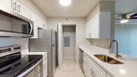 Located at 325 Speen St in Natick, Massachusetts, this single-floor residential unit offers a well-organized layout designed for comfortable everyday living. The spacious living area is a standout feature, finished with durable hardwood-style flooring, crown molding, and a ceiling fan with light fixture. A large sliding window opens to a private balcony, filling the room with natural light and providing outdoor views of the surrounding greenery. The open layout connects seamlessly to the kitchen pass-through, enhancing the sense of flow throughout the space.

The galley-style kitchen is efficiently designed and well-appointed, featuring white shaker cabinetry, light quartz countertops, and a full suite of stainless steel appliances including a refrigerator, electric range, built-in microwave, and dishwasher. Light tile flooring completes the clean, modern aesthetic.

The bedrooms are carpeted for comfort and feature neutral gray walls, generous natural light from windows with vertical blinds, and dedicated closet space with built-in rods. The bathroom is finished with classic black-and-white mosaic tile flooring, white subway tile surrounding the shower-tub combination, and a mirrored vanity. Throughout the unit, a neutral color palette and consistent finishes create a cohesive and inviting atmosphere.