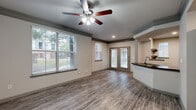 Located at 11212 Westpark Dr in Houston, TX, this single-story, one-bedroom, one-bathroom unit offers a well-organized layout with modern finishes throughout. Wood-look plank flooring flows consistently across all rooms, creating a cohesive and easy-to-maintain interior.

The open-concept living area is bright and airy, featuring multiple windows with blinds that frame outdoor greenery views, a ceiling fan with light kit, and decorative crown molding with a contrasting gray trim detail. French doors provide additional natural light and outdoor access. The kitchen is seamlessly integrated into the living space via a peninsula-style breakfast bar topped with dark granite countertops. White shaker-style cabinetry, a subway tile backsplash, stainless steel appliances — including a refrigerator, range, and microwave — and open corner shelving complete the kitchen.

The bedroom is a comfortable, well-proportioned space with its own ceiling fan, a window with natural light, and direct access to a spacious walk-in closet equipped with wire shelving on multiple walls for generous storage. The bathroom features a full tub-shower combo, granite vanity countertop, and brushed nickel fixtures. A dedicated in-unit laundry area accommodates a full-size washer and dryer with overhead shelving for added utility.