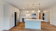 This thoughtfully designed two-bedroom, one-bathroom unit is laid out on a single floor, offering an efficient and functional use of space. The open-concept kitchen and living area serves as the centerpiece of the unit, featuring a striking kitchen with white shaker-style cabinetry extending to the ceiling, a herringbone tile backsplash, stainless steel appliances, and a large central island topped with a white quartz countertop. Three globe pendant lights suspended from brass fixtures add a modern, stylish touch overhead. Warm hardwood-style flooring runs throughout the main living areas, complementing the clean, neutral color palette.

The living area opens directly to a private balcony through large sliding glass doors, allowing abundant natural light to fill the space and offering views of the surrounding community, including a pool area. The two bedrooms are carpeted and well-proportioned, with the primary bedroom featuring a large window with outdoor views. A dedicated closet provides additional storage. The bathroom is finished in an all-white palette with a full soaking tub and shower combination, a white vanity with black hardware, and hardwood-style flooring, maintaining the unit's cohesive modern aesthetic throughout.