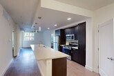 Located at 111 W Harrison St in Corona, CA, this well-appointed 2-bedroom, 3-bathroom residence offers a thoughtfully designed single-floor layout. The open-concept kitchen serves as the centerpiece of the home, featuring a generous island with a built-in sink, light quartz countertops, dark espresso cabinetry, stainless steel appliances including a gas range, microwave, and refrigerator, and stylish pendant lighting overhead. Wood-style flooring runs throughout the main living areas, lending warmth and continuity to the space. The kitchen flows seamlessly into the living area, which is brightened by large windows that invite natural light. Both bedrooms are carpeted and well-proportioned, with the primary bedroom offering a comfortable retreat. Two closets provide ample storage throughout the unit. The three bathrooms are finished with clean, modern details including dark wood vanities, white countertops, and wood-look tile flooring. A hallway connects the main living areas to the private quarters. Outdoor access reveals a beautifully landscaped courtyard with a resort-style pool, lush tropical plantings, and a pergola seating area — ideal for relaxing or entertaining in the Southern California climate.
