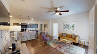 This thoughtfully designed 2-bedroom, 2-bathroom residence delivers a seamless open-concept floor plan on a single level. The kitchen is a standout feature, equipped with dark gray cabinetry, granite countertops, a white subway tile backsplash, and a full suite of black appliances including a refrigerator, range, microwave, and dishwasher. A large center island with a granite surface and an undermount sink provides additional prep space and casual bar seating beneath stylish pendant lighting. The kitchen flows naturally into a spacious living and dining area, where rich wood-style flooring, a ceiling fan, and a private entry door with a window create an inviting, airy atmosphere. Both bedrooms are carpeted and feature ceiling fans, offering a quiet and comfortable retreat. The primary bedroom includes a walk-in closet and an en-suite bathroom with granite countertops, dark cabinetry, and wood-style flooring. The second bathroom mirrors the same finishes and includes a full soaking tub with a shower. Neutral wall tones throughout the unit provide a clean, versatile backdrop that complements a variety of design styles, making this a well-appointed and functional home.