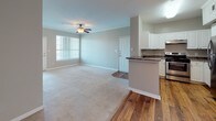 Located at 25 Johnny Mercer Blvd in Savannah, Georgia, this single-floor unit offers a well-designed, open layout with a comfortable and functional living environment. The spacious living area features plush carpeting, crown molding, and a ceiling fan, creating a relaxed atmosphere. Natural light flows in through large windows fitted with blinds, offering pleasant outdoor views of the surrounding Savannah landscape.

The kitchen is thoughtfully appointed with white cabinetry, dark granite-style countertops, warm hardwood flooring, and a full suite of stainless steel appliances including a refrigerator, electric range, dishwasher, and range hood. A raised breakfast bar provides a seamless transition between the kitchen and the adjacent dining area, which also features hardwood floors and a decorative pendant light.

Each bedroom is generously sized, carpeted for comfort, and equipped with a ceiling fan. Large windows in the bedrooms allow for ample natural light and outdoor views. The bathroom continues the cohesive design aesthetic with white cabinetry, matching dark countertops, a single-basin sink, and hardwood flooring, complemented by a shower-tub combination. Throughout the unit, neutral gray tones and white trim create a clean, modern, and inviting atmosphere.