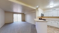 Located at 2539 Troon Ct in Elkhart, Indiana, this single-floor residence offers a functional, open-concept layout designed for comfortable everyday living. The living area is generously proportioned, featuring neutral-toned carpet, crisp white walls, and a sliding glass door that fills the space with natural light and provides access to an outdoor balcony area. Structural ceiling beams add subtle architectural character to the room.

The kitchen flows directly from the living space via a peninsula-style breakfast bar, creating a seamless connection ideal for entertaining or casual dining. White shaker-style cabinetry provides ample storage, complemented by light countertops, stone-tile flooring, a stainless steel gas range, and a built-in microwave. A refrigerator is also included. Louvered closet doors adjacent to the kitchen offer additional convenient storage.

The bedroom features plush carpeting and bright, neutral walls, creating a calm and restful environment. The bathroom is well-appointed with stone-look tile flooring, a vanity with storage, and a tub-shower combination, maintaining a clean and practical aesthetic throughout. Overall, the space presents a tidy, move-in-ready environment with a cohesive neutral palette.