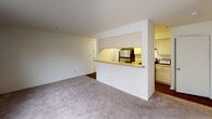 This single-floor residential unit offers a clean, functional layout designed for comfortable everyday living. The open living area is finished with neutral-toned wall-to-wall carpeting and features a pass-through window connecting directly to the kitchen, creating a sense of openness between the two spaces. Natural light filters into the living and bedroom areas through slatted blinds, maintaining a bright and airy atmosphere throughout.

The kitchen is equipped with stainless steel appliances, including a refrigerator and an electric range, complemented by cream-colored cabinetry offering generous storage. Light-toned countertops and rich hardwood-style flooring complete the kitchen's practical and cohesive aesthetic. The kitchen also provides direct access to the unit's entry door.

The bedrooms are carpeted and generously sized, with one featuring convenient direct access to a private bathroom as well as a dedicated walk-in closet, providing ample storage. Both bedrooms receive natural light through windows fitted with blinds.

The unit includes two bathrooms. The primary bathroom offers a vanity with under-cabinet storage, a large mirror, and a shower-tub combination. The secondary bathroom mirrors this layout with a vanity, mirror, and shower-tub with curtain, both finished with hardwood-style flooring. Overall, the unit presents a straightforward, well-maintained interior suitable for a variety of living arrangements.