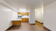 Located at 100 Richmond Rd in Euclid, Ohio, this two-bedroom, one-bathroom unit offers a practical and well-organized single-floor layout. The living room is the largest area of the home, featuring light-toned wood-look flooring, crisp white walls, and a window that invites natural light and views of surrounding greenery, creating a clean and open atmosphere. The kitchen, visible in the dollhouse view, is equipped with wooden cabinetry and a range, providing a functional space for everyday cooking. Both bedrooms carry the same wood-look flooring and neutral white walls, maintaining a consistent and airy aesthetic throughout. Each bedroom is fitted with sliding closet doors featuring gold-toned frames, offering practical storage. The primary bedroom is generously sized with room for a full furniture arrangement, while the second bedroom also benefits from natural light via a window. The full bathroom includes a tiled tub-shower combination with chrome fixtures, a toilet, and a clean white finish. Dark wood baseboards run throughout the unit, adding a subtle contrast to the light floors and walls. The overall design is understated and move-in ready, offering a comfortable and functional living environment.