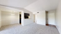 Located at 5915 Flintlock Rd in Houston, TX, this one-bedroom, two-bathroom residence offers a thoughtfully arranged single-floor layout. The open living room is a standout space, featuring vaulted ceilings, plush carpet, and a classic brick wood-burning fireplace. Sliding glass doors flood the room with natural light and provide direct access to a private patio, creating a seamless indoor-outdoor flow. The adjacent galley kitchen is well-equipped with dark espresso cabinetry, granite-style countertops, hardwood flooring, and black appliances, including a refrigerator and dishwasher. A pass-through counter connects the kitchen to the living area. The spacious primary bedroom is carpeted and includes a ceiling fan, a natural light-filled window, and access to a dedicated walk-in closet with built-in shelving and rods. Both bathrooms feature hardwood flooring, dark vanity cabinetry with granite-style countertops, and mirrored fixtures. One bathroom includes a full tub-shower combination with white tile surround. The neutral color palette and consistent finishes throughout lend the space a cohesive, functional aesthetic suitable for comfortable everyday living.