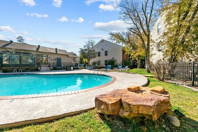 Community swimming pool with concrete surround, blue lounge chairs, mature trees, and adjacent clubhouse - Walnut Creek