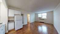 Located at 901 Montgomery Ave in Bryn Mawr, PA, this single-floor unit offers a functional and well-appointed layout highlighted by warm parquet hardwood flooring that extends throughout the living areas. The open main living space is generously proportioned, with white walls, clean lines, and natural light streaming through multi-pane windows. A radiator unit and wall-mounted air conditioner provide year-round climate control.

The kitchen is efficiently arranged, featuring white cabinetry with upper storage, a coil-burner electric range, a full-size refrigerator, and a sink—all compactly positioned to maximize usability. A charming glass-paned French door adds a classic architectural detail between the kitchen and living areas.

A dedicated closet space off the main living area provides ample storage with built-in shelving and hanging rods. The bathroom showcases timeless black-and-white tile work, with white square wall tiles accented by a bold black border, a single vanity sink, and a full bathtub. A utility area accommodates a stacked washer and dryer unit, adding everyday convenience. The entry foyer provides a welcoming transition into the space, completing this practical and characterful Bryn Mawr residence.