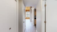 Located at 2 N Main St in Beacon Falls, CT, this one-bedroom, one-bathroom unit showcases a striking industrial-loft aesthetic rooted in its historic building origins. The open living area commands attention with soaring ceilings clad in warm natural wood planking, exposed timber beams, and original brick accent walls. Large, multi-pane windows line the space, inviting abundant natural light and offering views of the surrounding greenery and neighboring architecture. Light-toned hardwood-style flooring runs throughout, complementing the airy, open feel of the main living area, which also features a ceiling fan for added comfort.

The kitchen is efficiently appointed with light maple cabinetry, dark granite countertops, stainless steel appliances including a range, microwave, refrigerator, and dishwasher, and durable tile flooring — a functional and well-equipped space.

The bedroom continues the loft character with soaring ceilings, exposed wood beam detailing, and large windows that bathe the room in natural light while offering outdoor views.

The bathroom is clean and well-maintained, featuring a combined tub and shower, light wood vanity cabinetry with a stone-finish countertop, a large mirror, and tile flooring. Chrome fixtures and grab bars add a polished, practical finish to the space.