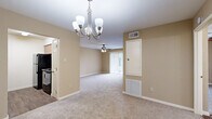 Located at 16 Charleston Park Dr in Houston, TX, this single-story, one-bedroom, one-bathroom residence offers a practical and comfortable layout across a compact but well-utilized floor plan. The open living and dining area is a welcoming space finished with neutral beige walls and plush carpeting throughout. An elegant chandelier anchors the dining area, while a ceiling fan with integrated lighting serves the living room, which benefits from a sliding glass door fitted with vertical blinds that invites natural light and provides outdoor access. The galley-style kitchen is efficiently designed, featuring warm wood-toned cabinetry, laminate countertops, a double-basin sink, and black appliances including a refrigerator and range. Rich wood-look flooring adds warmth and easy maintenance to this space. The bedroom is a comfortable retreat with carpeted floors, a ceiling fan, a window with natural light, and a large sliding-panel closet offering generous storage. The bathroom features a wood-vanity with a single-basin sink, laminate countertop, and a well-lit mirror with overhead strip lighting, complemented by wood-look tile flooring. The overall ambiance is clean, neutral, and move-in ready.