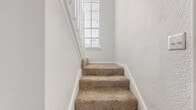 Located at 14300 Tandem Blvd in Austin, TX, this one-bedroom, one-bathroom multi-level home spans three floors and offers a thoughtfully designed layout with generous living space throughout. The main level serves as the heart of the home, featuring a spacious living area with soaring vaulted ceilings, a classic fireplace, and plush carpeting. A sliding glass door opens to a private balcony, filling the room with natural light and providing outdoor access. Adjacent to the living area, the kitchen is outfitted with white cabinetry, dark countertops, and dark hardwood-style flooring, offering a clean and functional workspace. A staircase with a white-painted railing leads up to a loft-style open area — a versatile space with angled ceilings, a ceiling fan, and a window that brings in additional natural light. The bedroom is a well-proportioned retreat featuring carpet flooring, a ceiling fan, and a closet. The bathroom features a dual-sink vanity with light stone countertops, white cabinetry, and wood-style flooring. A dedicated laundry area adds everyday convenience. With its dramatic vertical architecture, multi-level design, and bright, neutral palette throughout, this home offers a distinctive and functional living experience in Austin, TX.