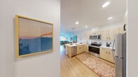 Located at 11201 Roosevelt Way NE in Seattle, WA, this well-designed one-bedroom, one-bathroom residence offers a thoughtfully efficient layout with modern finishes throughout. Light hardwood flooring flows seamlessly across the entire space, creating a cohesive and inviting atmosphere.

The open-concept kitchen is a standout feature, showcasing light wood cabinetry with matte black hardware, white quartz countertops, a peninsula with bar seating, pendant lighting, and a full suite of stainless steel appliances including a refrigerator, electric range, and microwave. The kitchen transitions naturally into the living area, which benefits from large windows that invite abundant natural light and offer views of the surrounding Seattle neighborhood.

The bedroom is a calm, comfortable retreat with a large window providing additional natural light and neighborhood views, complemented by warm-toned hardwood floors. The full bathroom features matching light wood cabinetry, a white quartz vanity, and a tub-shower combination. A dedicated in-unit laundry closet houses a stacked washer and dryer for added convenience. The residence also includes a separate closet for storage. Clean white walls and recessed lighting throughout contribute to the space's bright, modern character.