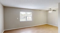 This one-bedroom, one-bathroom unit in West Columbia, SC offers a practical and well-organized single-floor layout. The living room is bright and open, featuring durable wood-look flooring, neutral-toned walls, a textured ceiling, and a window fitted with blinds that allows natural light to fill the space. A ceiling fan with integrated lighting provides comfort and illumination. The living area connects conveniently to the kitchen, which is equipped with white upper cabinetry, light-toned countertops, and a stainless steel refrigerator, all set against clean, bright finishes and matching wood-look flooring. A hallway leads to the private bedroom, a comfortably sized room with plush carpeting, neutral walls, a textured ceiling, and two doors — one accessing a closet and the other opening to the hallway — offering both storage and privacy. The bathroom includes a full tub and shower combo with a clean white surround and chrome fixtures. Throughout the unit, consistent neutral tones, white trim, and clean finishes create a cohesive and move-in-ready aesthetic suitable for everyday living.