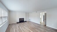 Located at 73 Denise Dr in Burlington, NC, this two-floor home offers a well-organized layout with a clean, neutral aesthetic throughout. The spacious living room serves as the heart of the home, anchored by a floor-to-ceiling white painted brick fireplace with a sleek black surround. Wood-look flooring runs throughout the main living areas, complemented by natural light streaming through large windows dressed with horizontal blinds. The kitchen is thoughtfully updated with white shaker cabinetry, granite-patterned countertops, a stainless steel double-basin sink, and stainless steel appliances including an electric range and over-range microwave. A dedicated laundry room provides added convenience with a full-size washer and dryer. The bedrooms feature soft neutral carpet and generous closet space, including sliding-door closets with built-in rods. Two full bathrooms each include a tub-shower combination with white subway tile surrounds and chrome fixtures, maintaining a clean and classic look. The overall ambiance of the home is bright, clean, and move-in ready, with a consistent neutral color palette that provides a versatile backdrop throughout both floors.